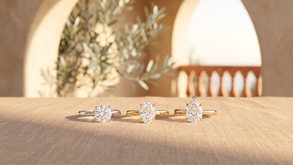 Round, oval and pear diamond solitaire rings in white, yellow and rose gold on linen